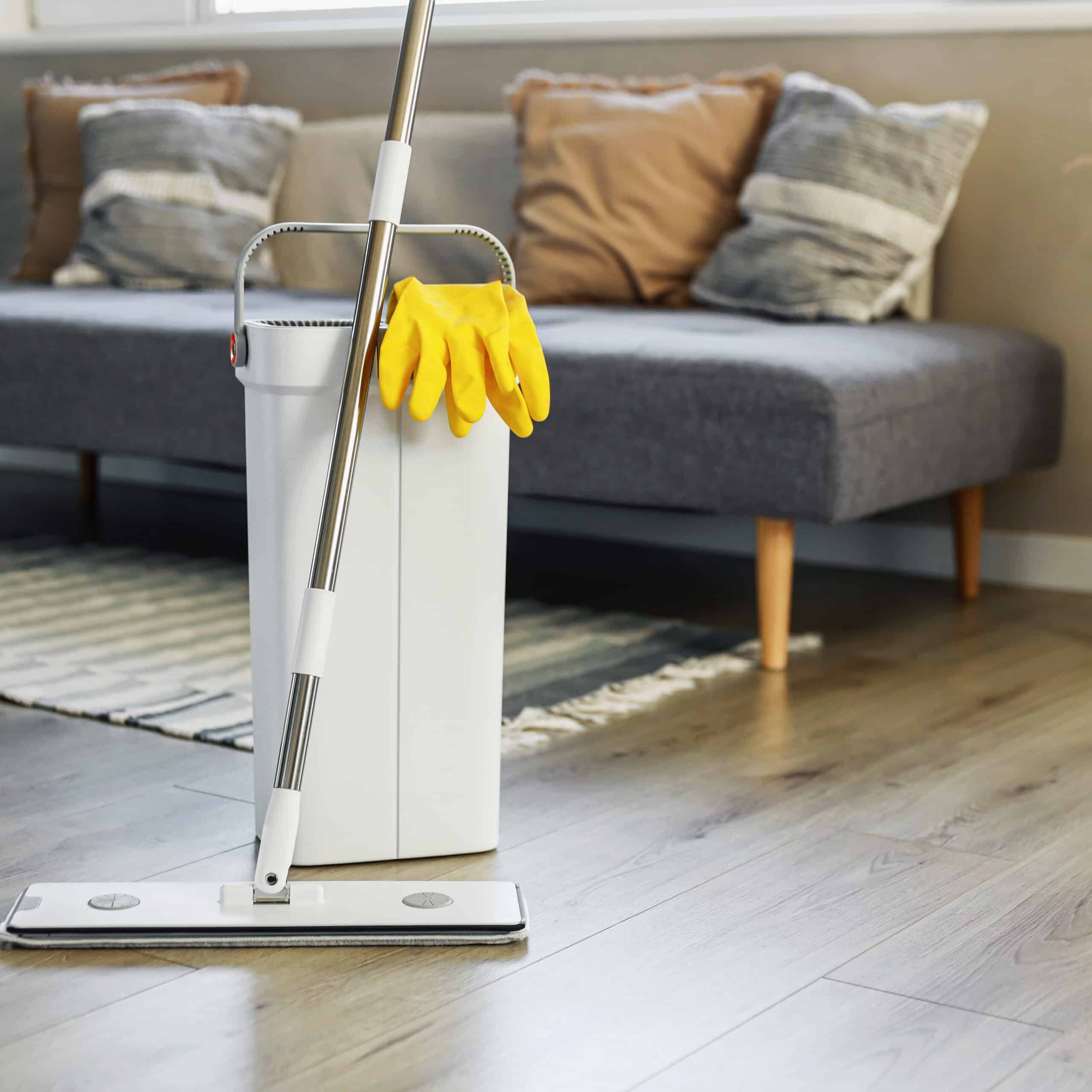 Cleaning supplies: mop, gloves, bucket with wringer on wooden laminate floor