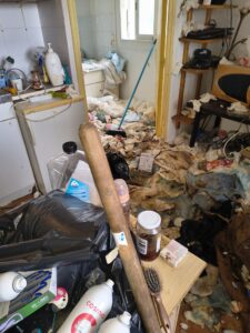 Intérieur insalubre encombré de déchets, sacs et produits Cosmia illustrant un syndrome de Diogène extrême.