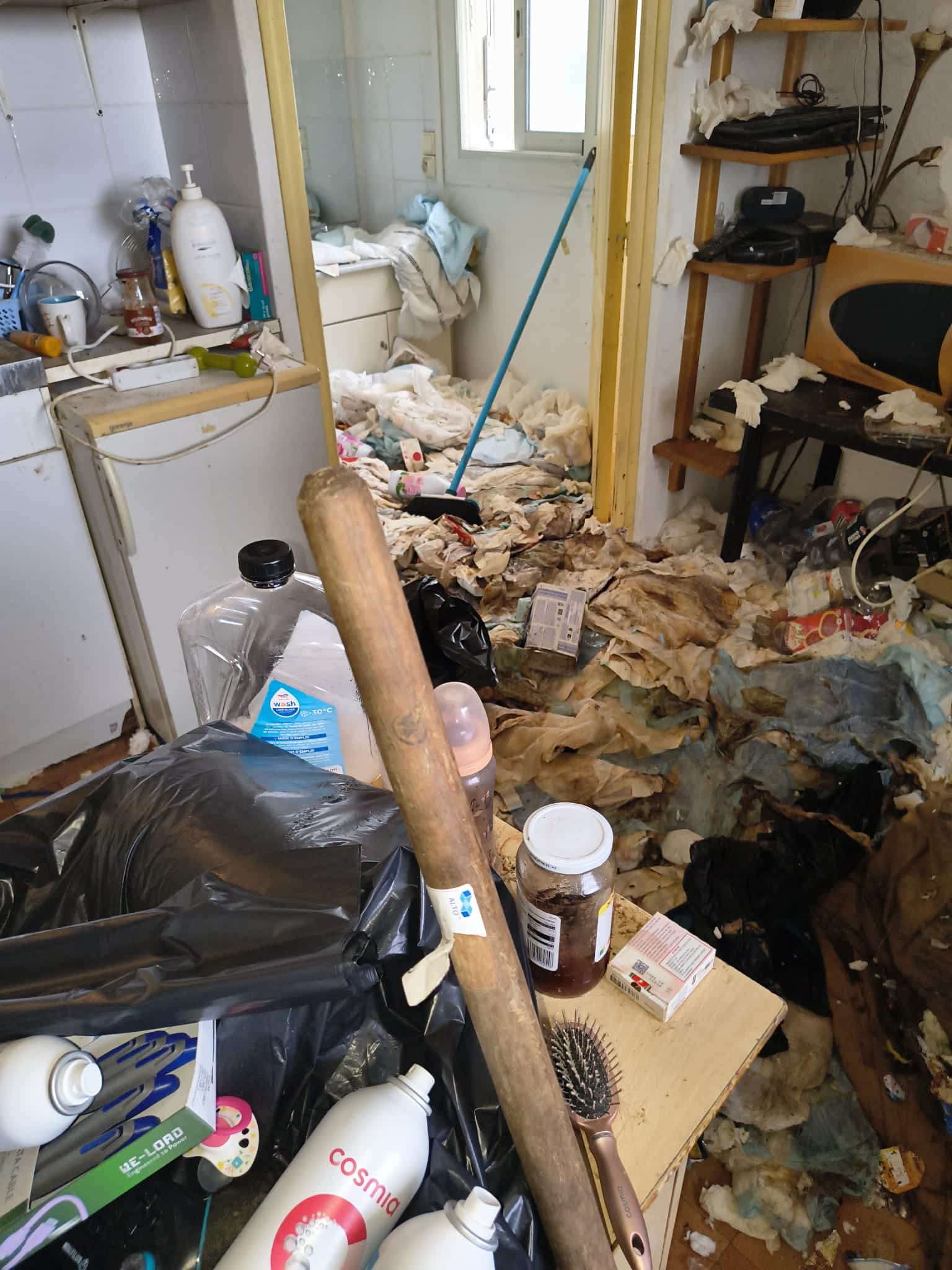 Intérieur insalubre encombré de déchets, sacs et produits Cosmia illustrant un syndrome de Diogène extrême.