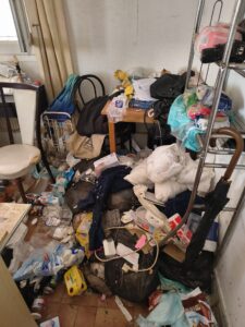 Logement insalubre saturé de déchets, sacs et emballages Aldi au sol. Accumulation extrême et désordre massif.
